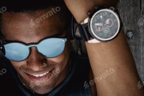 Preview: Young fit man with sunglasses working out in the park while listening to music in headphones