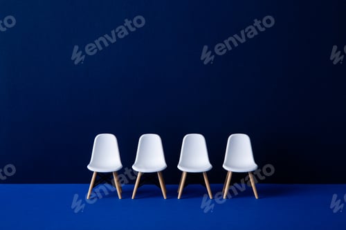 Preview: Four empty white chairs in the waiting room symbolizing recruitment and leadership