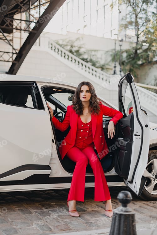Preview: beautiful sexy rich business woman in red suit posing in white car