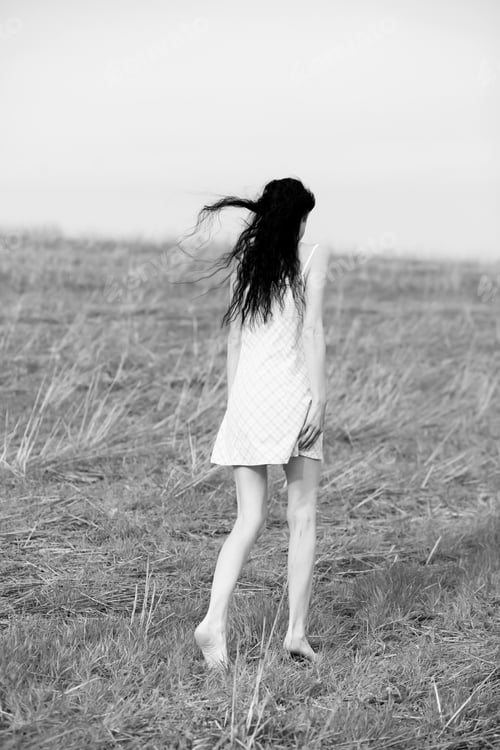 Preview: A beautiful girl is walking through a wheat field at sunset.