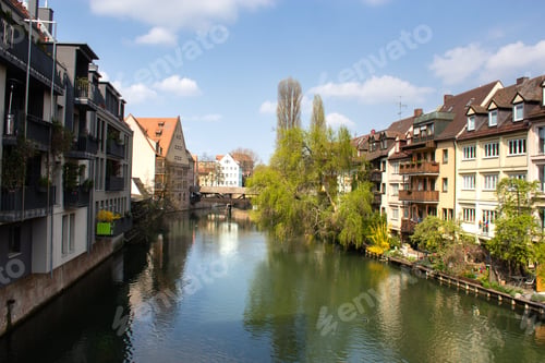 Preview: River surrounded by greenery and buildings under the sunlight and a blue sky