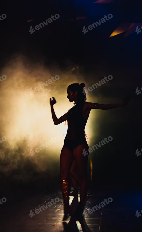 Preview: silhouette of a woman dancing between lights and smoke