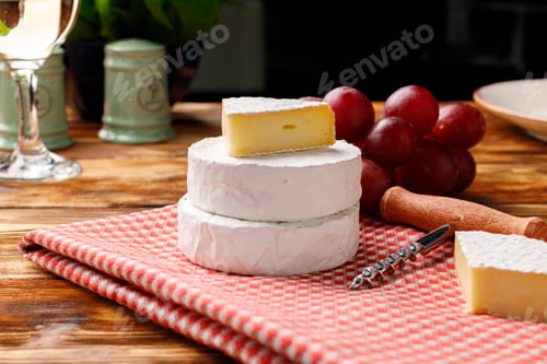 Preview: Round white cheese with grapes on wooden table
