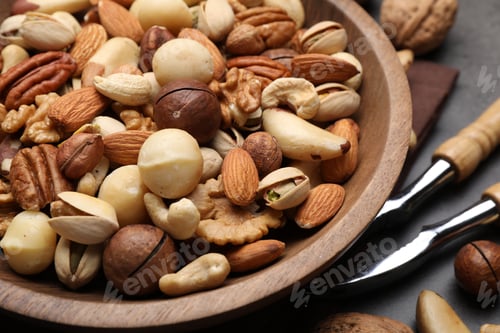 Preview: Mix of different nuts in bowl and nutcracker on grey table, closeup