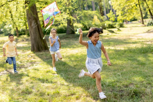 Preview: Little Asian girl running happily with a kite in the park