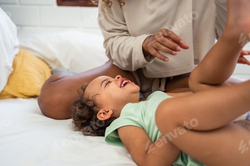 Preview: African loving mom play with cute baby girl child on bed in bedroom.