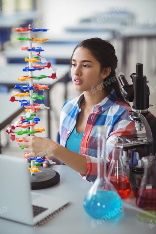 Preview: Attentive schoolgirl experimenting molecule model in laboratory