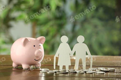 Preview: Pension savings. Figures of senior couple, piggy bank coins on wooden table outdoors