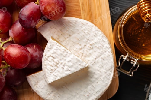 Preview: Cheese served with grapes and honey on grey surface