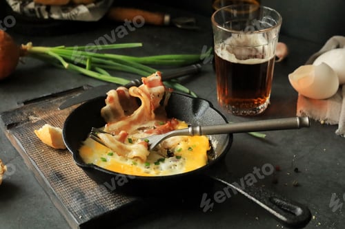 Preview: Fried eggs with bacon in a frying pan on the table, beer and other food products for lunch