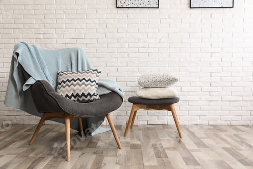 Preview: Stylish interior with plaid, pillows and armchair near brick wall, space for text