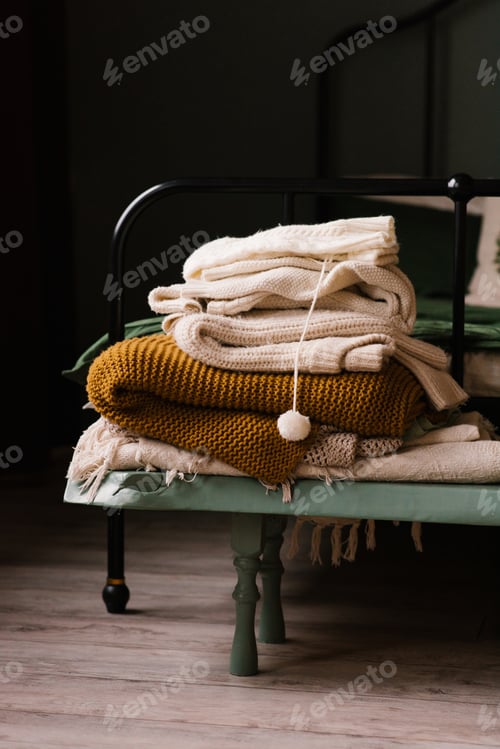 Vista previa: Stack of Knitted Blankets and Sweaters in a Cozy Winter Bedroom