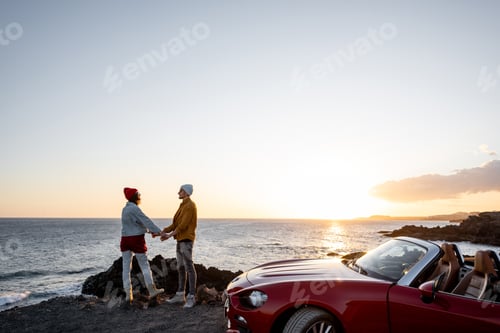 Preview: Lovely couple on the beach near the car on a sunset