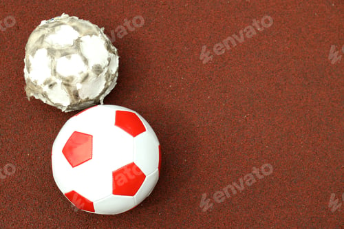 Preview: Two football balls on playground rubber coating