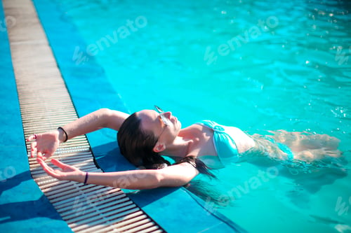 Preview: Beautiful young girl relaxing in the swimming pool outdoors