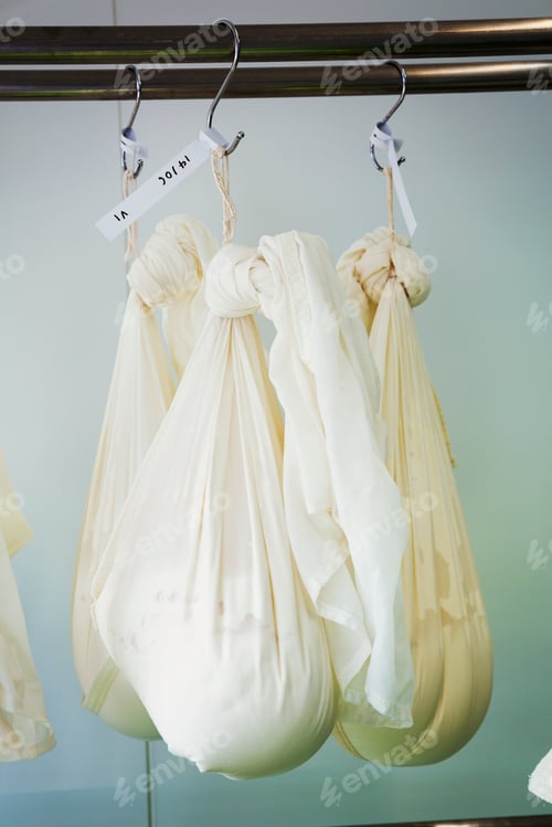 Preview: Gauze bags with goats cheese hanging in a creamery.