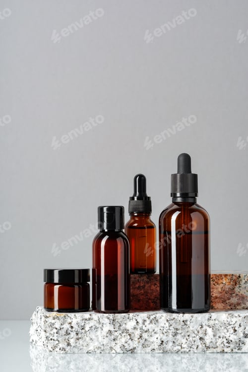 Preview: Set of brown glass bottles with essential oils on stand on gray background