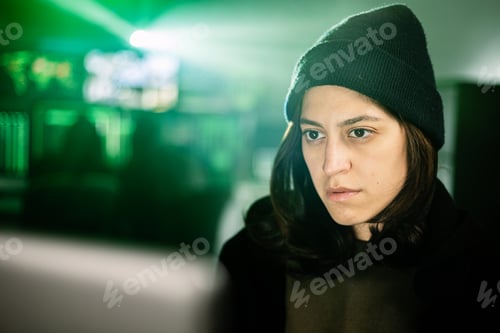 Preview: Female hacker working on laptop in dark room