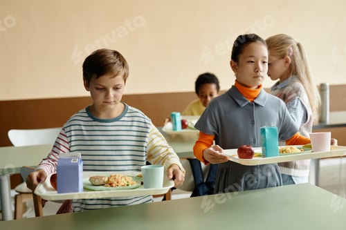 Preview: Two Children Holding Trays of Lunch at Table in School Cafeteria