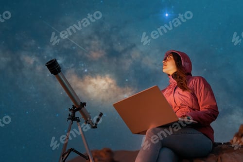 Preview: woman sitting in the desert with a laptop next to a telescope at night watching the starry sky