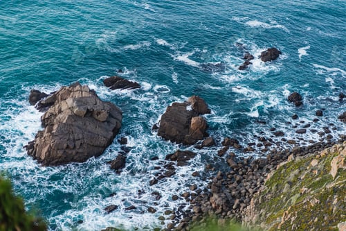 Preview: Blue waves crash against the rocky shore.