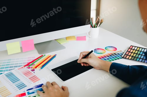 Preview: Freelance creative designers working on desk using digital graphic tablet and drawing with pen