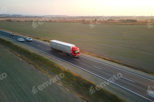 Preview: Aerial view of blurred fast moving semi-truck with cargo trailer driving on highway