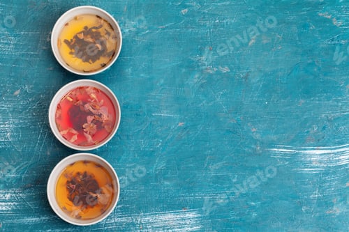 Preview: Tea concept. Different kinds of dry tea in ceramic bowls and cups of aromatic tea
