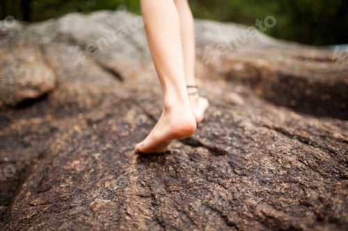 Preview: behind young person walking on rock barefoot