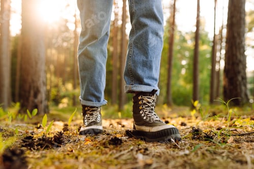Preview: Feet of an adult wearing boots to travel walking in the forest. Feet walking in outdoor nature