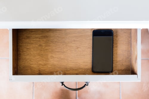 Preview: High angle shot of a phone in a wooden drawer