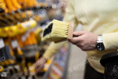 Preview: a man in a hardware store holding a paintbrush close-up