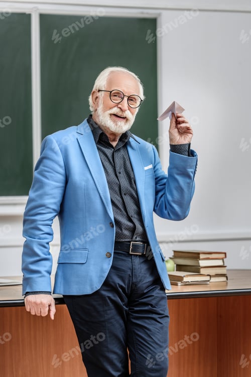 Preview: smiling grey hair professor holding paper plane in lecture room