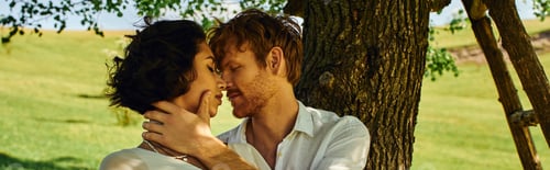 Preview: just married interracial couple with closed eyes embracing under tree in rural setting, banner