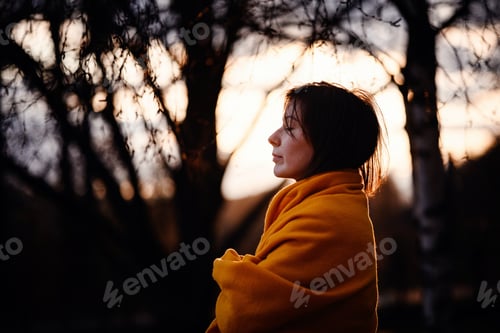 Preview: Woman Wrapped in Orange Blanket at Peaceful Sunset