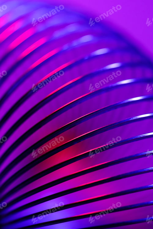 Preview: Closeup of coiled metal spring with sufficiently high strength and elastic properties in neon light