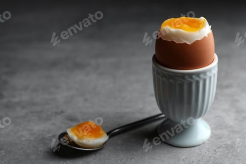 Preview: Fresh soft boiled egg in cup on grey table. Space for text