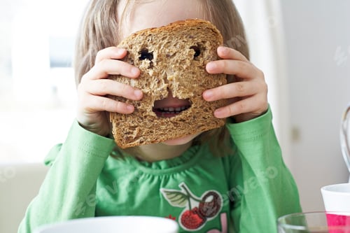 Preview: Little girl looking through holes in slice of bread