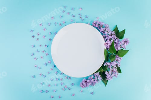 Preview: A plate with copy space around violet lilac on a blue background.
