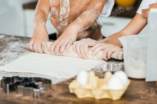 Preview: partial view of children holding rolling pin and preparing dough for delicious cookies