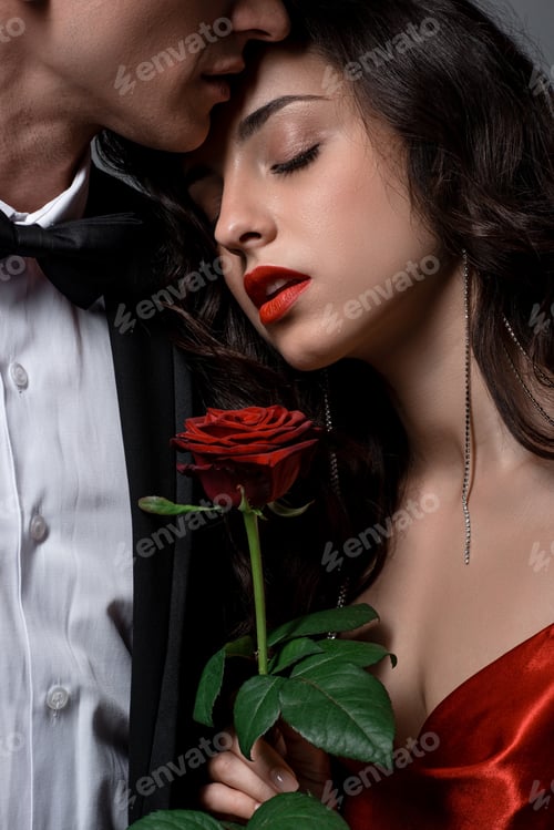 Preview: cropped view of Romantic couple hugging and holding red rose flower