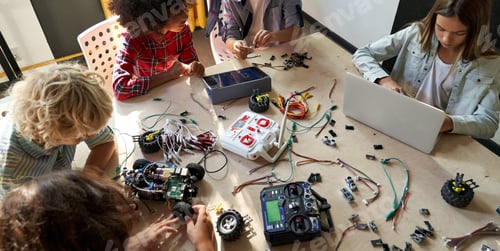 Preview: Group of multiracial schoolkids at stem class building robot. Table top view.