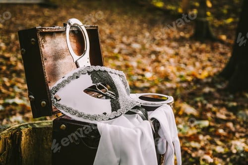 Preview: Selective focus of a handcuff, mascarade, and white fabric gloves on an opened wooden chest