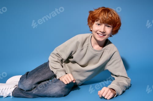 Preview: Stylish little boy poses playfully on a vibrant blue background with cheerful expression