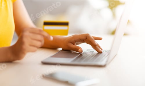 Preview: Black lady using laptop and debit credit card at home