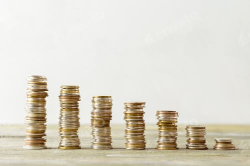 Preview: Stacks of coins arranged in different heights on a wooden surface for comparison purposes
