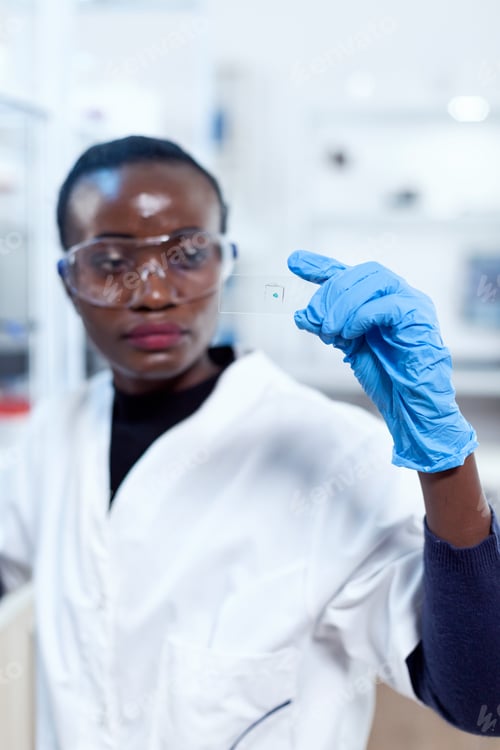 Preview: Close up of african biochemists holding microscope sample