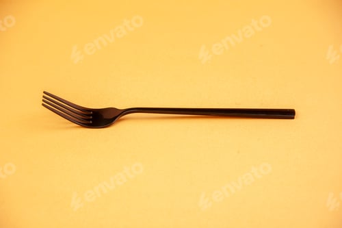 Preview: Top view of elegant metal fork on golden color background with free space