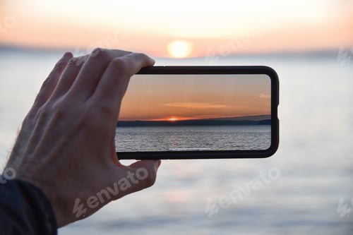 Preview: Point of view taking a sunset photo with smart phone camera.