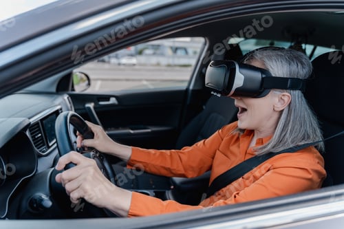 Preview: Senior woman wearing virtual reality glasses, driving car with open mouth.